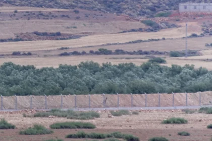 Συρματοπλέγματα και φράχτης διασχίζουν ξηρή πεδιάδα με ελαιόδεντρα στα σύνορα Μαρόκου και Αλγερίας