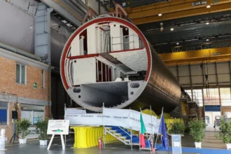 Τμήμα κελύφους υποβρυχίου U212NFS σε υπόστεγο του ναυπηγείου της Fincantieri στο Μουτζιάνο, με την ιταλική και την ευρωπαϊκή σημαία μπροστά του