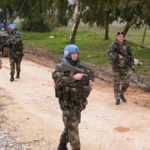 Ιρλανδοί κυανόκρανοι και Λιβανέζοι στρατιώτες περπατούν σε χωματόδρομο δίπλα σε φράχτη στη νότια Λίβανο
