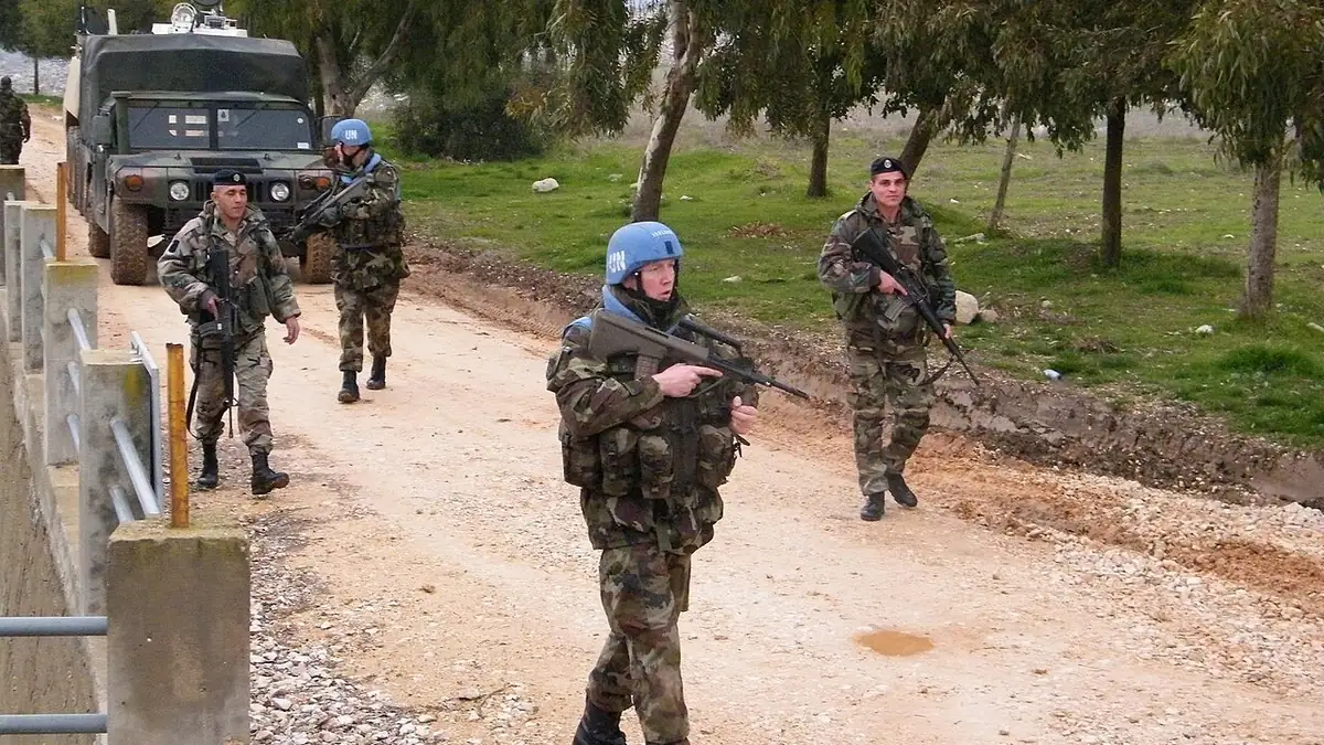 Ιρλανδοί κυανόκρανοι και Λιβανέζοι στρατιώτες περπατούν σε χωματόδρομο δίπλα σε φράχτη στη νότια Λίβανο
