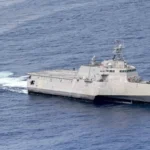 Το USS Charleston (LCS 18), πλοίο κλάσης Independence με τριμαράν γάστρα, πλέει στον ωκεανό με ένα μικρό σκάφος στο βάθος