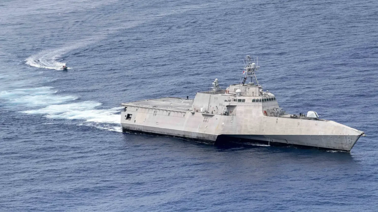 Το USS Charleston (LCS 18), πλοίο κλάσης Independence με τριμαράν γάστρα, πλέει στον ωκεανό με ένα μικρό σκάφος στο βάθος