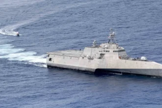 Το USS Charleston (LCS 18), πλοίο κλάσης Independence με τριμαράν γάστρα, πλέει στον ωκεανό με ένα μικρό σκάφος στο βάθος