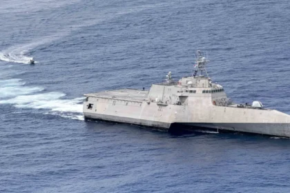 Το USS Charleston (LCS 18), πλοίο κλάσης Independence με τριμαράν γάστρα, πλέει στον ωκεανό με ένα μικρό σκάφος στο βάθος