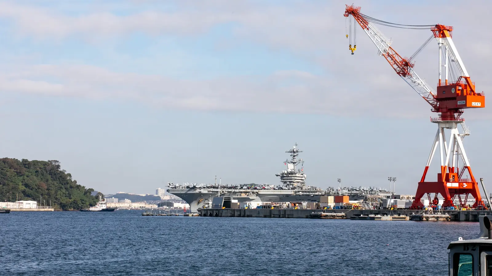 Το αεροπλανοφόρο USS Theodore Roosevelt στο βάθος του λιμανιού της Γιοκοσούκα, με λιμενικό γερανό σε πρώτο πλάνο