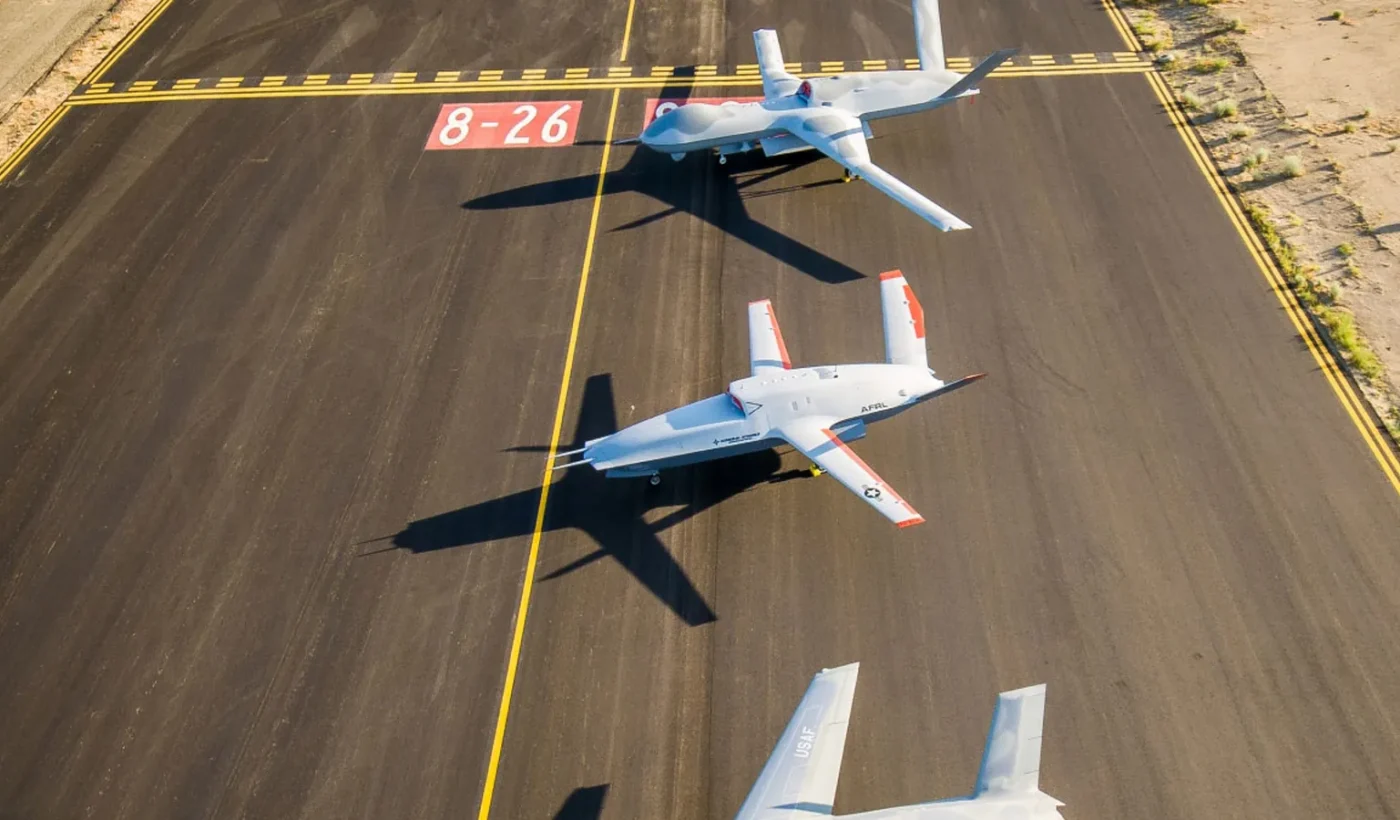 Τρία αεροσκάφη, ανάμεσά τους το MQ-20 Avenger και το XQ-67A, σε διάδρομο αεροδρομίου από ψηλά