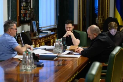 Ο Βολοντίμιρ Ζελένσκι και συνεργάτες του κάθονται σε μακρύ τραπέζι με έγγραφα κατά τη διάρκεια συνομιλίας