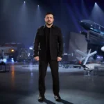 Ο Ουκρανός πρόεδρος Βολοντίμιρ Ζελένσκι όρθιος σε αίθουσα με ουκρανικής κατασκευής πυραύλους, drones και οχήματα